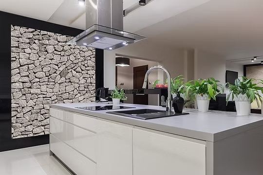 Modern white kitchen island with sink, faucet, and stone accent wall