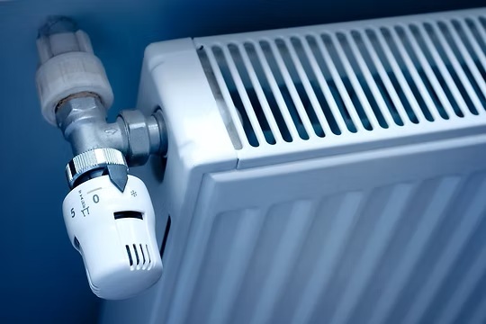 Close-up of a white radiator with an adjustable thermostatic valve